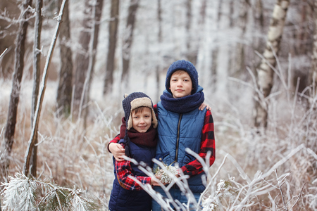 Two brothers on walr in winter forest. Best friends playing together.の写真素材