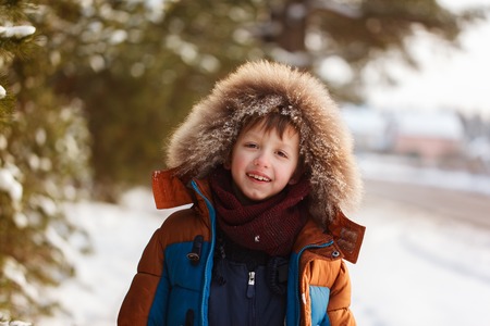Happy child walking in a winter forest in sunny day.の写真素材