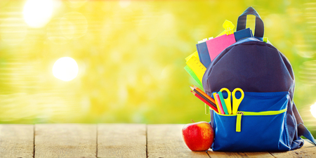 Full School backpack with apple on wooden and nature green background. Banner.の写真素材