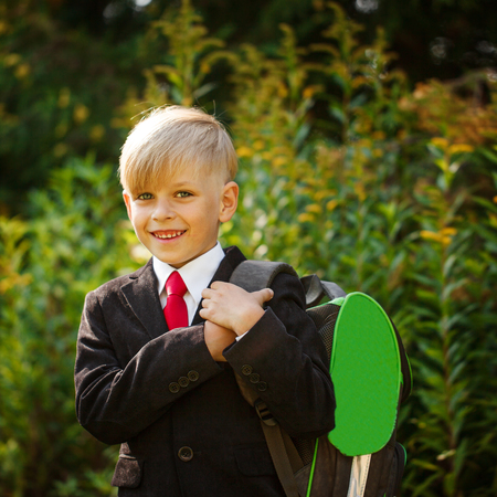 Cute boy going back to school. Boy in the suit. Closeup portrait of smiling pupil with backpack on first school day.の写真素材