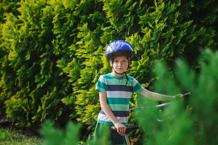 Portrait little boy in helmet on a bicycle at asphalt road in the summer park.の写真素材