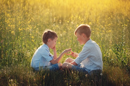 Two little boys friends playing - stone, scissors, paper- game in summer day. Concept of fun and...