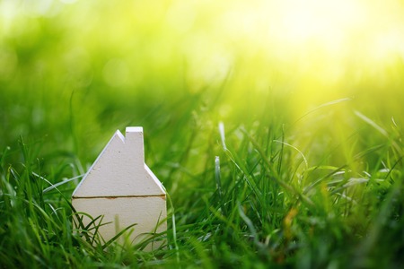 Small model wooden white house over green grass background.の写真素材