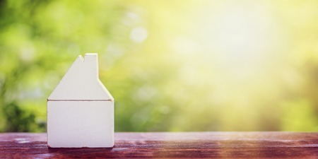 White wooden small model of home on table and green nature background. Banner.の写真素材