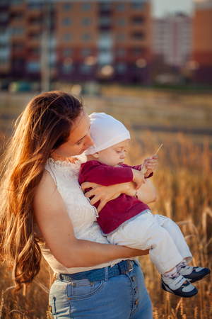 Young mother with her cute child, enjoying the sunny day over summer fieldの写真素材