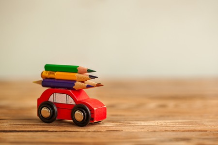 Miniature Red Car Carrying a colorful pencils on wooden table. Back to school concept.の写真素材
