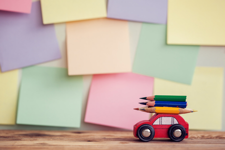 Back to school background with Miniature Red Car Carrying a colorful pencils over colorful stikers on wall.の写真素材