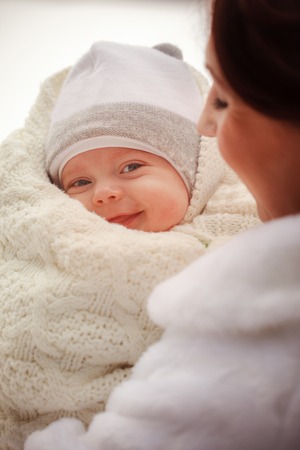 CLoseup portrait of child. Mother holds on hands her little baby on winter walk outdoors
