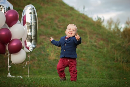 Handsome smile portrait baby. 1 year old cute boy on the grass. Birthday anniversary