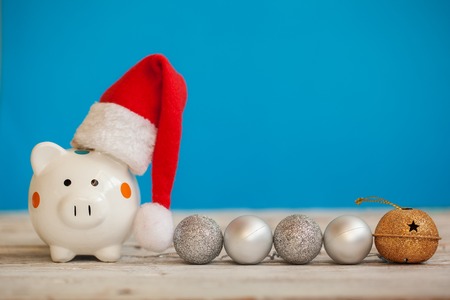 Piggy bank with santa claus hat on blue background. Christmas and New Year conceptの写真素材