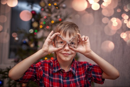 Adorable little boy is preparing the gingerbread, bake cookies in the Christmas kitchen