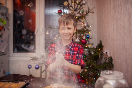 Funny little boy is preparing the biscuit, bake cookies in the Christmas kitchen