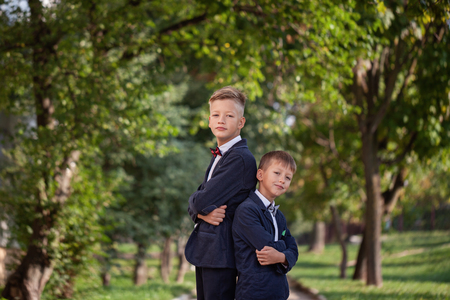 Happy two boys standing back to back on nature background in summer day.の写真素材