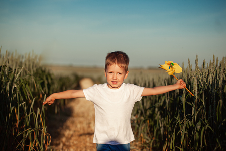 Cute little boy running and holdingwindmill in hand in summer dayの写真素材