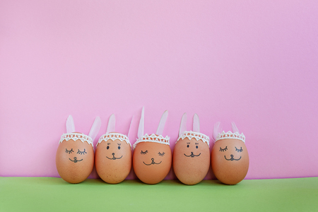 Funny easter bunnies eggs on green and pink paper background with copy space. Happy Easter concept.の写真素材