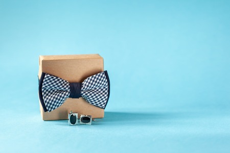 One gift box wrapped in craft paper and tied with the bow tie on blue background. Concept Fathers Day.の写真素材