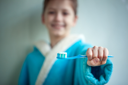 Child brushing teeth. Focus on the hand holding the toothbrush with the paste.の写真素材