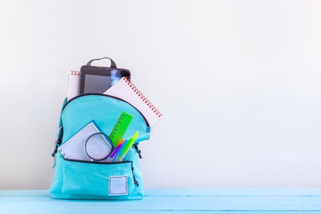 Full turquoise School Backpack with stationery on table. Concept back to school.