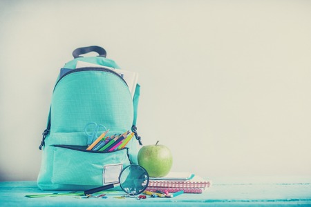 Full turquoise School Backpack with stationery on table. Concept back to school. Toned image.の写真素材