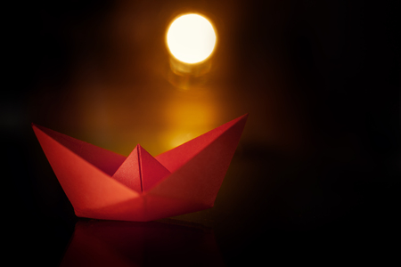 Paper sail boat on dark background. Red paper ship on sunset.の写真素材
