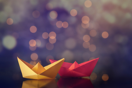 Red and yellow paper ship ships on dark background.の写真素材