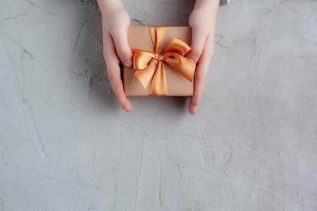 Children hands holding present box on grey netrual background. Time gifts.の写真素材