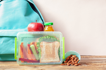 School lunch box with sandwich, vegetables, juice and almonds on table. Healthy eating habits concept.の写真素材