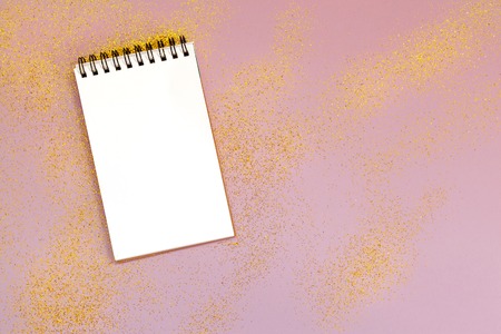 Empty pad with gold sparkles, stars and glitters on pink background. Festive concept.の写真素材