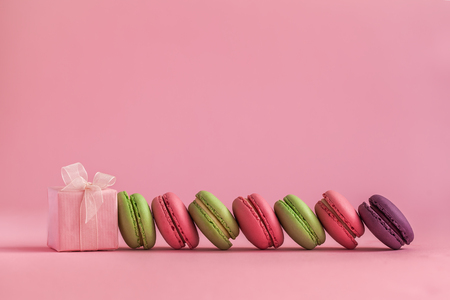 Pink present and Row of french colorful macaroons, lying on pink backgroundの写真素材