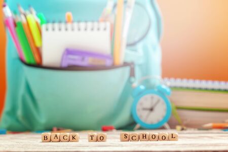 Concept back to school. School Backpack with different supplies and alarm clock on background.の写真素材