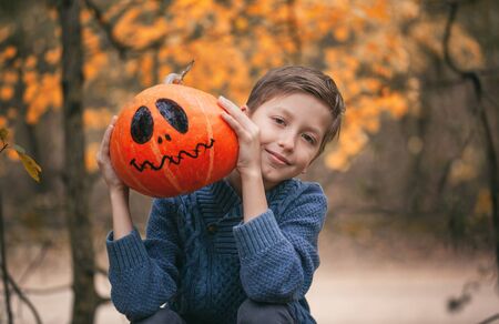 Boy holding a pumpkin. The concept of holidays. Preparing for Halloween. Harvest.の写真素材