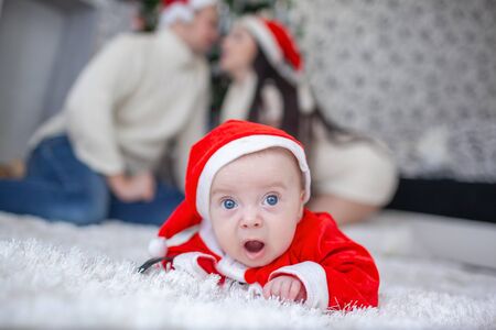 Portrait of newborn baby in Santa clothes and christmas hat, lying near Christmas tree.の写真素材
