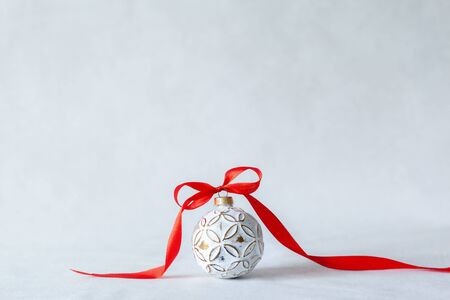 Christmas holidays composition with white ball and red ribbon on light background with copy space. Merry Christmas and New Year holidys background.の写真素材