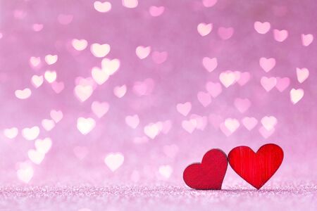 Valentine's day greeting card. Two red wood Heart shapes on abstract pink background in love...