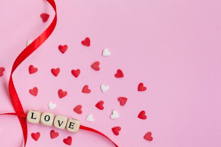 Valentines Day theme word "Love" with white and red hearts on pastel pink background. Valentines day concept. Flat lay, top view, copy spaceの写真素材