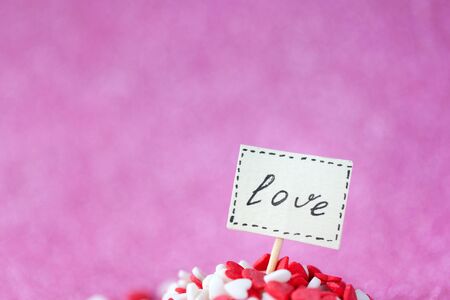 Valentine day concept. Love text composed on board in heap red and white hearts on pink background.の写真素材