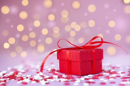 Red gift box and confetti hearts on pink background. 14 February Valentines day concept.