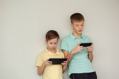 Two kids boys playing games or looking information video at Internet on mobile phones at home....
