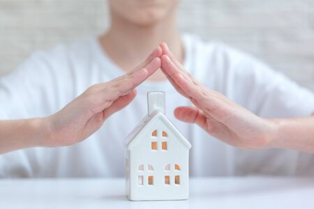 Children's Hands Over House on white background - Home Security And Protection Concept. Stay at home...