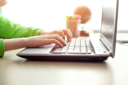 Close-up of kids hands, using laptop to learn from home. Digital concept remote e-learning ,...