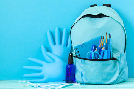 Backpack prepared with school stationery supplies and medical mask, gloves hand sanitizer for the back to school.の写真素材