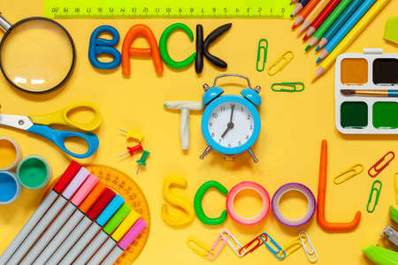 Back to school concept. Different colorful school supplies on yellow background with text back to...