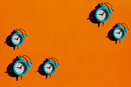 Blue alarm clock on orange background. Back to school concept. Creative design, minimal flat lay concept. Bannerの写真素材