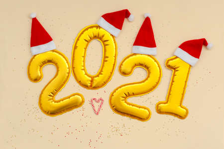 Happy New Year Golden digits 2021 numbers with christmas hat on beige background with confetti. New Year or Merry Christmas concept.の写真素材