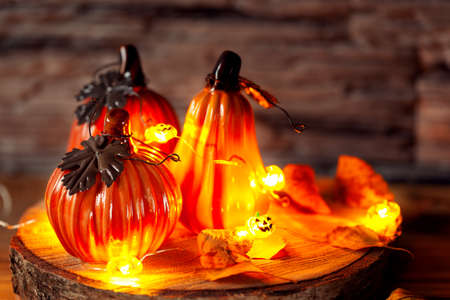 Holiday decoration with decorative ceramic pumpkins with decoration light Garland of glowing on wooden table. Halloween background.の写真素材