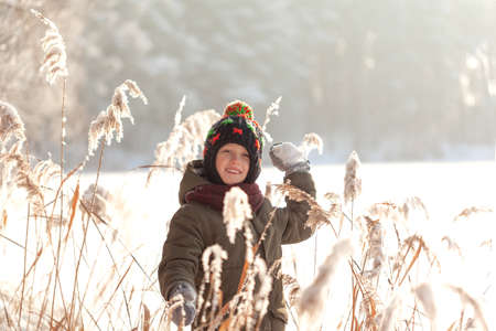 Wintertime. Cute boy having fun playing with fresh snow in winter forest. Active leisure outdoors for kid in snowy winter dayの写真素材