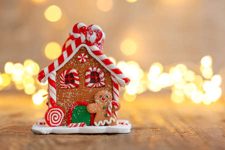 Gingerbread house under a Christmas tree with defocused lights. Christmas holiday mood concept.