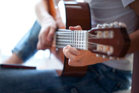 Closeup of hands teenager playing acoustic guitar. Have a hobby. Relaxing boy playing guitar. Soft...