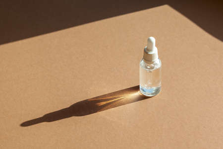 Cosmetic dropper bottle for serum, micellar toner and emulsion on brown background. Skin care, hydration and nutrition oxygen bubbles. Beauty product.の写真素材