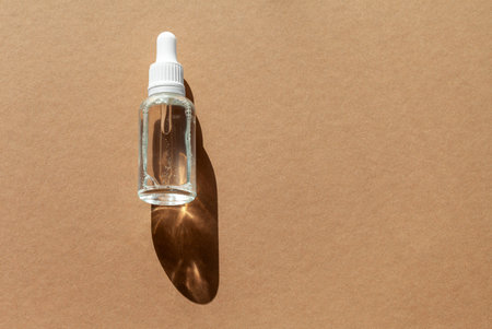 Cosmetic dropper bottle for serum, micellar toner and emulsion on brown background. Skin care, hydration and nutrition oxygen bubbles. Beauty product.の写真素材
